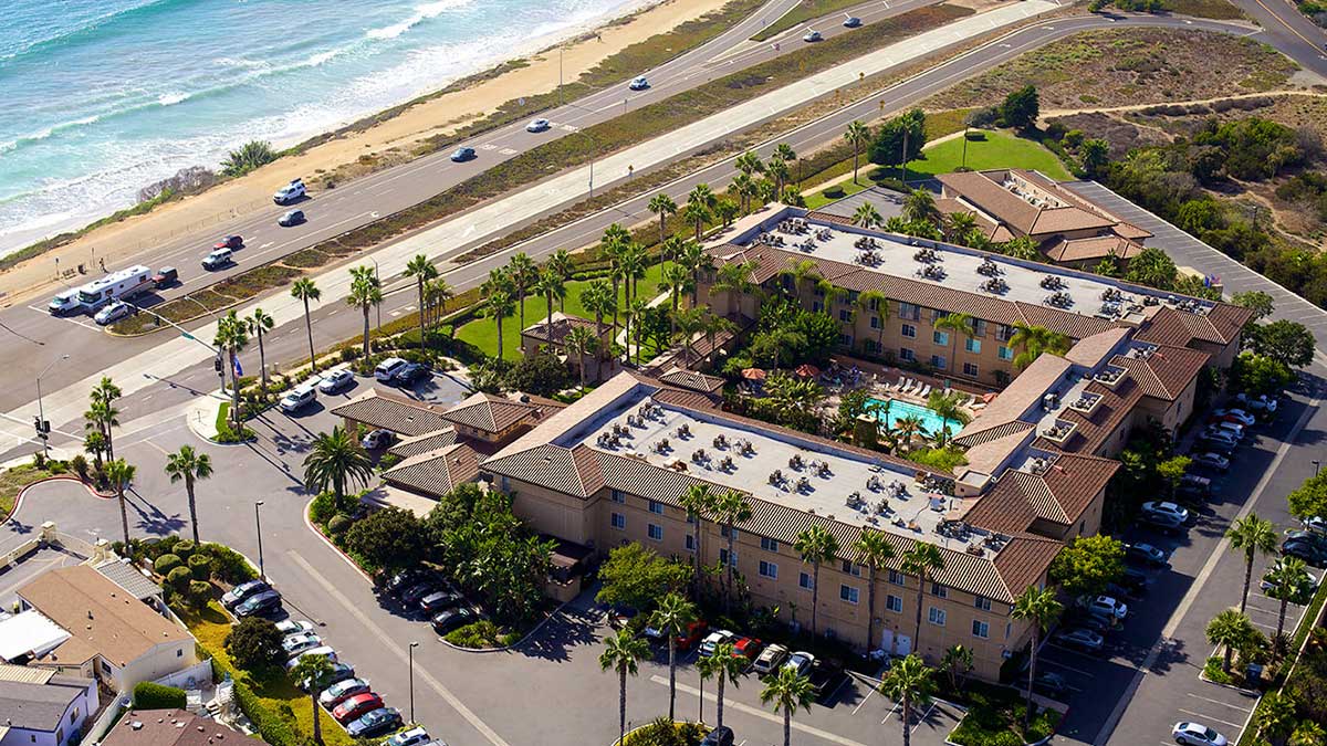 aerial view of Hilton Garden Inn Carlsbad Beach with palms trees and cars and road and nearby beach in San Diego, California, USA